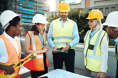 Buy stock photo Shot of a diverse group of contractors standing outside together and having a discussion over building plans