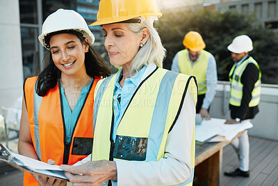 Buy stock photo Shot of two contractors standing outside together and having a discussion over a clipboard