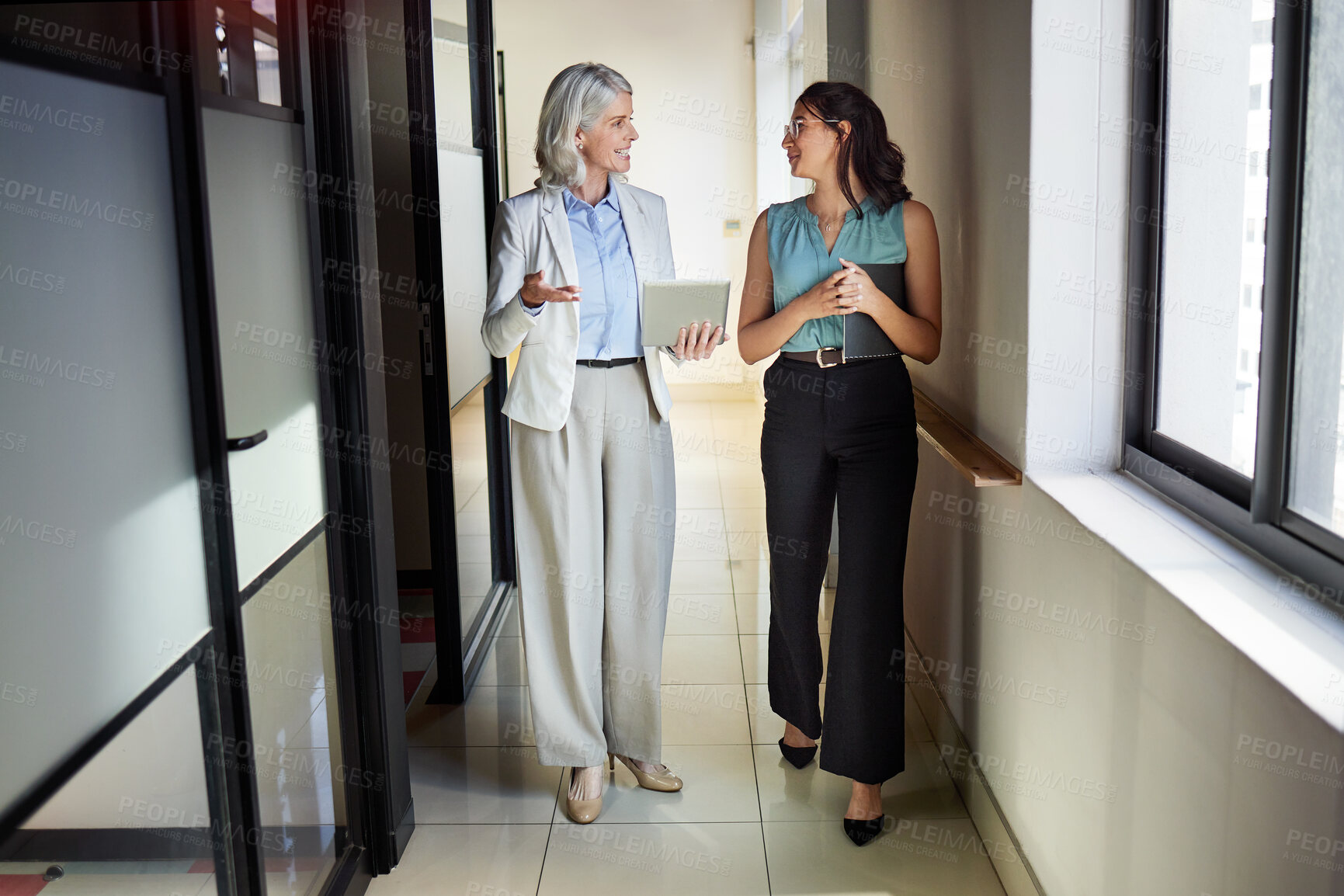 Buy stock photo Full length shot of two businesswomen standing in the office together and having a discussion