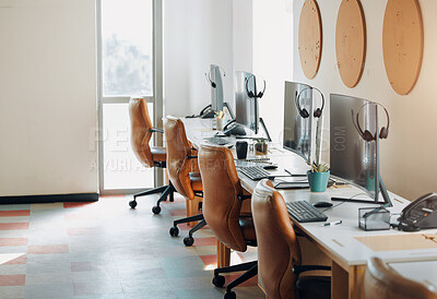 Buy stock photo Shot of desktops and headsets in an empty office during the day
