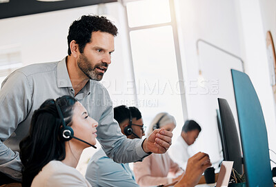Buy stock photo Shot of a mature businessman standing and talking to a young agent while she uses her computer