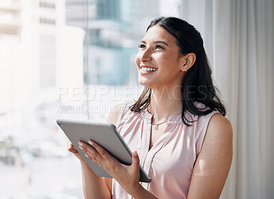Buy stock photo Shot of an attractive young businesswoman standing alone in the office and looking contemplative while using a digital tablet