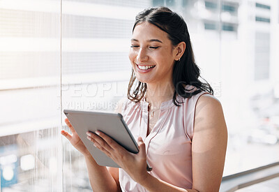 Buy stock photo Shot of an attractive young businesswoman standing alone in the office and using a digital tablet