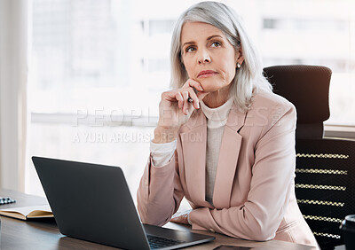 Buy stock photo Shot of a mature businesswoman sitting alone in the office and looking contemplative while using her laptop
