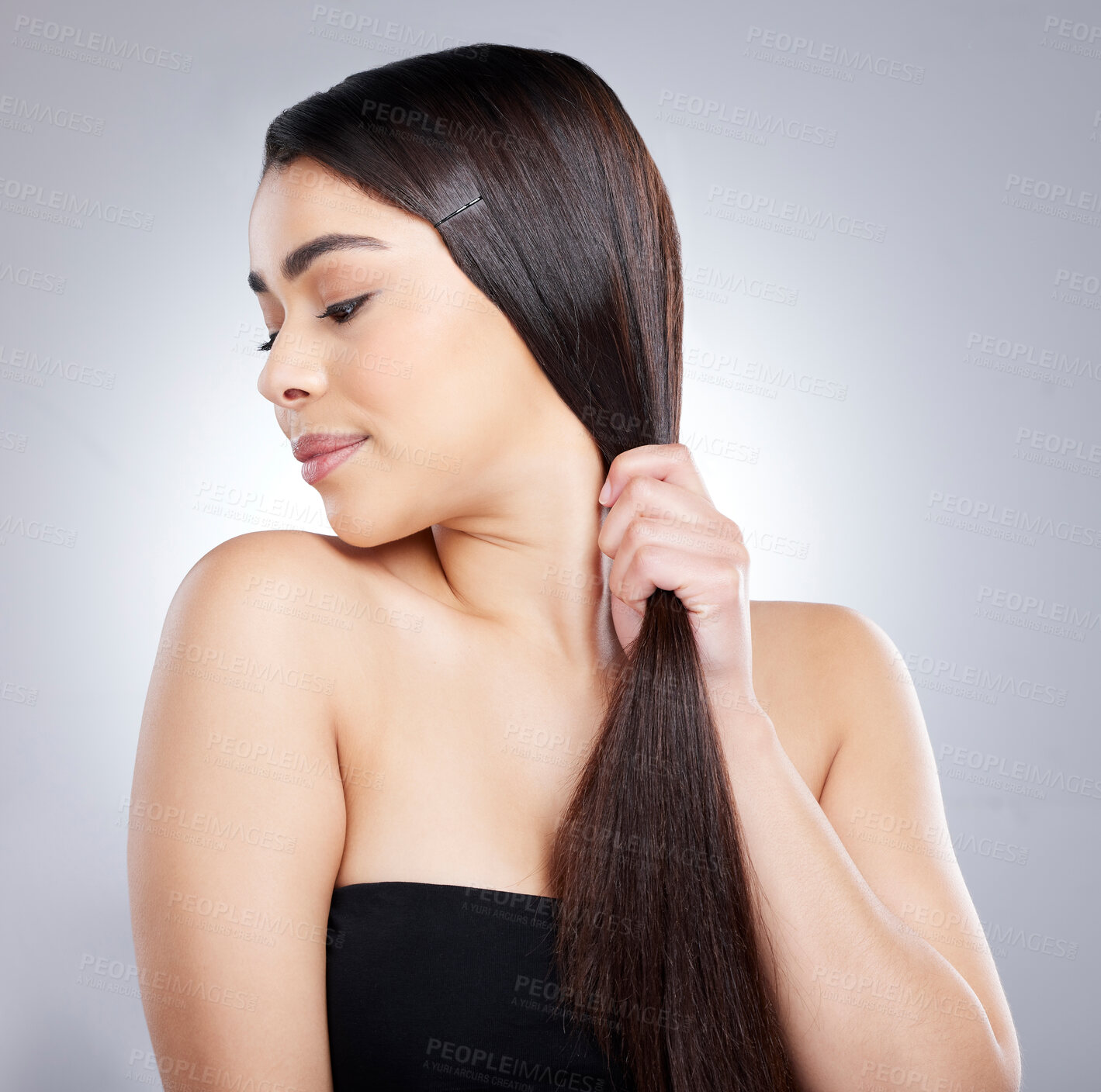 Buy stock photo Studio shot of an attractive young woman brushing her hair against a grey background