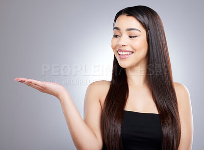 Buy stock photo Studio shot of an attractive young woman pointing to copyspace against a grey background