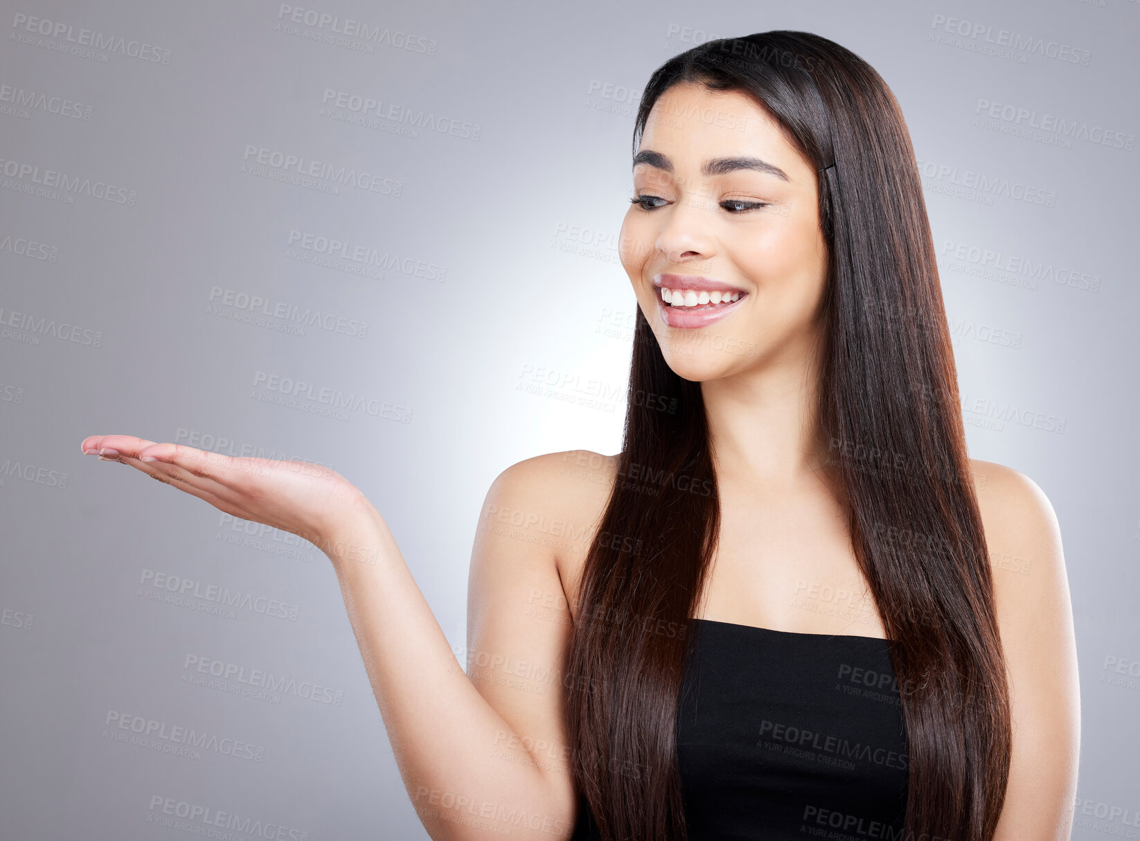 Buy stock photo Studio shot of an attractive young woman pointing to copyspace against a grey background