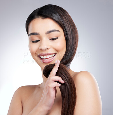 Buy stock photo Studio shot of an attractive young woman brushing her hair against a grey background