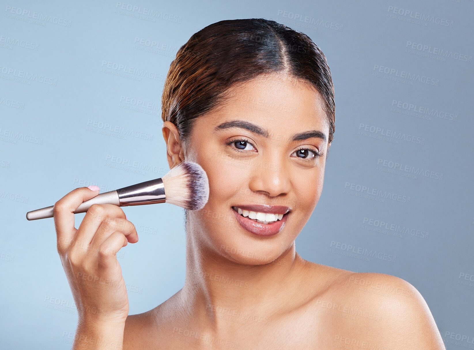 Buy stock photo Shot of a young woman applying makeup to her face against a grey background