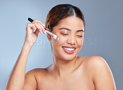 Buy stock photo Shot of a young woman applying makeup to her face against a grey background