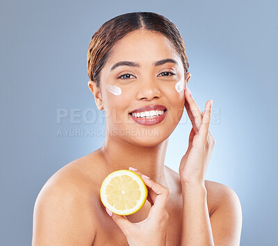 Buy stock photo Shot of a young woman holding half a lemon against a grey background