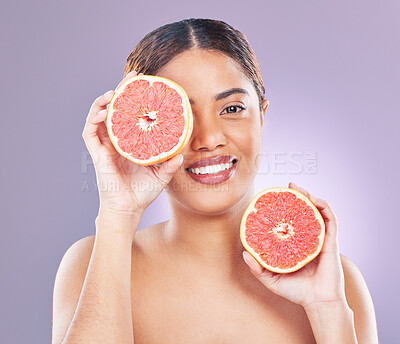 Buy stock photo Shot of a young woman holding two halves of a grapefruit against a pink background