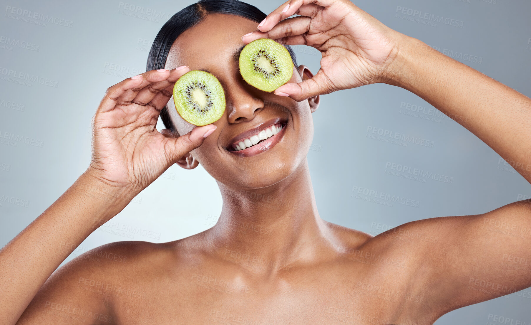 Buy stock photo Happy woman, kiwi slices and beauty with fruit in studio for wellness, health or silly face for treatment. Organic skincare, cosmetics and results, goofy and dermatology for glow in gray background