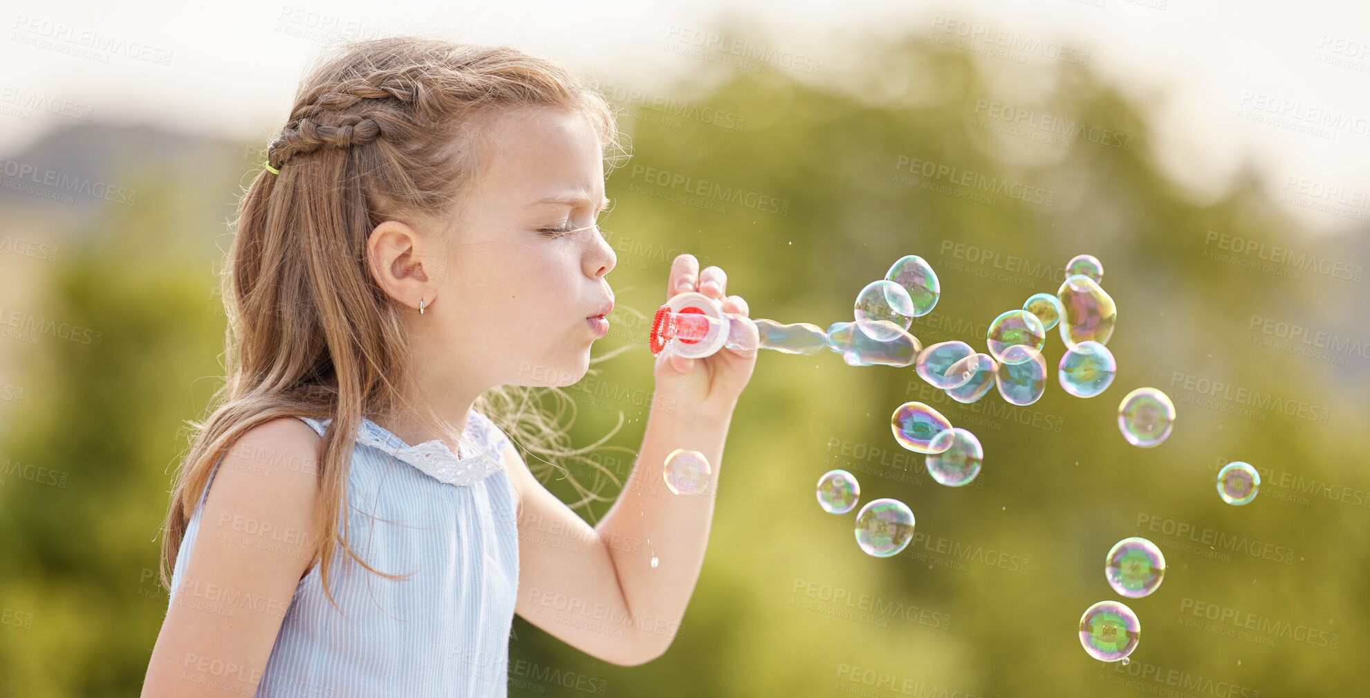 Buy stock photo Shot of a little girl blowing bubbles in a park