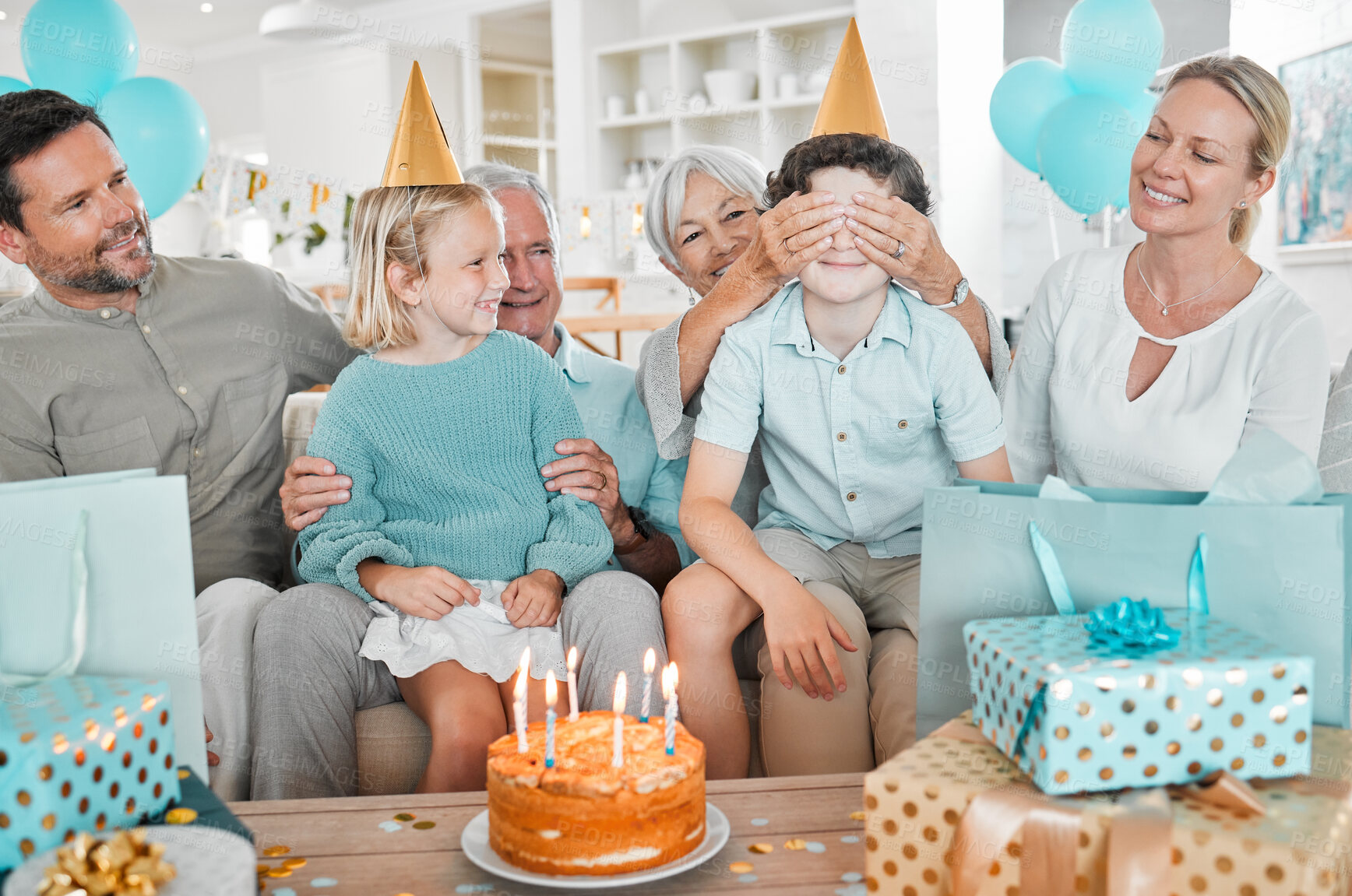 Buy stock photo Parents, boy and grandparents in home for birthday party with cake, games or siblings with with blindfold for surprise. People, playful and kids on sofa for present, excited or dessert at family house