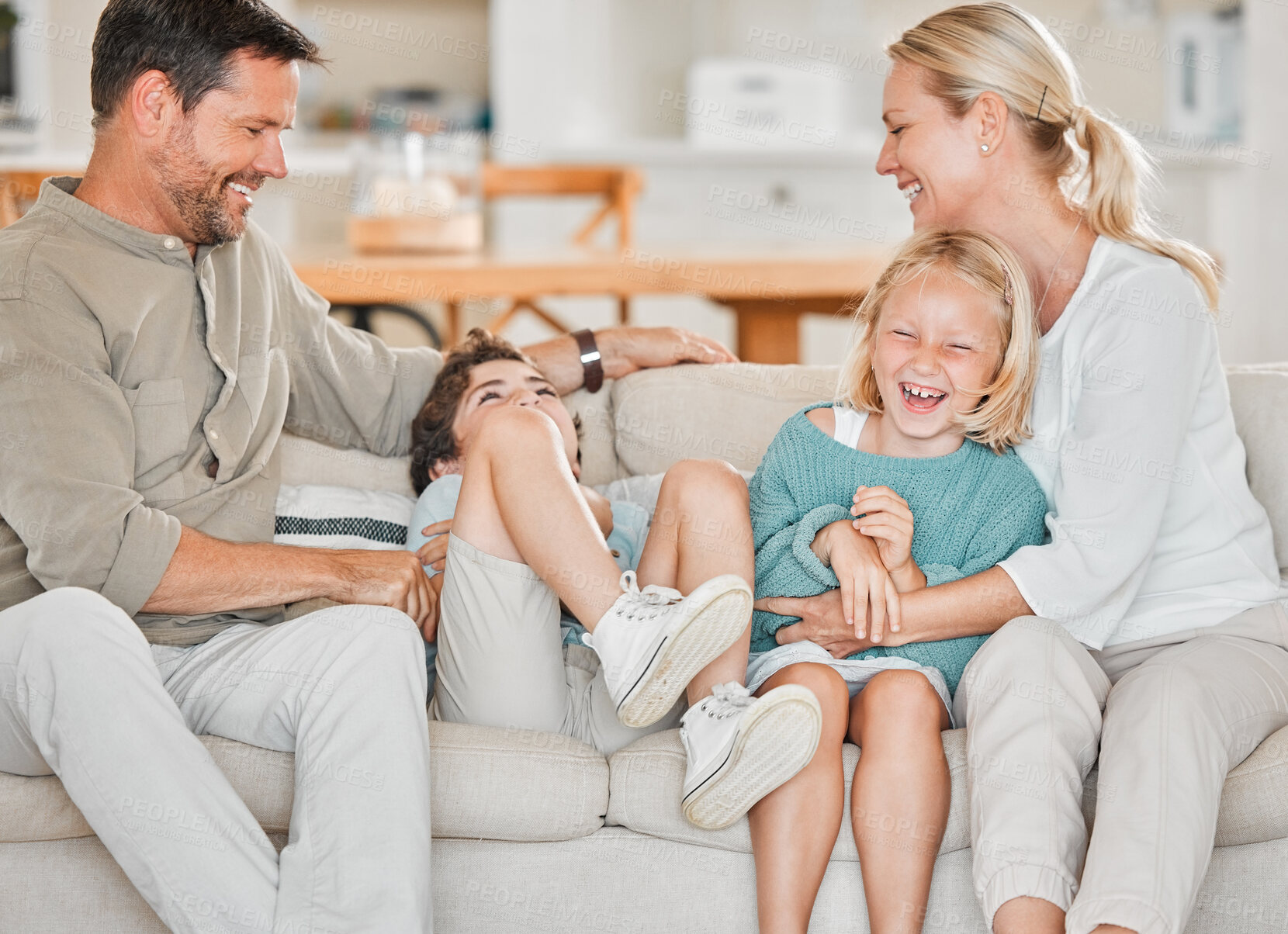 Buy stock photo Parents, children and laughing for playing on sofa with tickle, affection and happy relationship in home. Family, people and kids on couch with bonding, connection and enjoyment for love and care