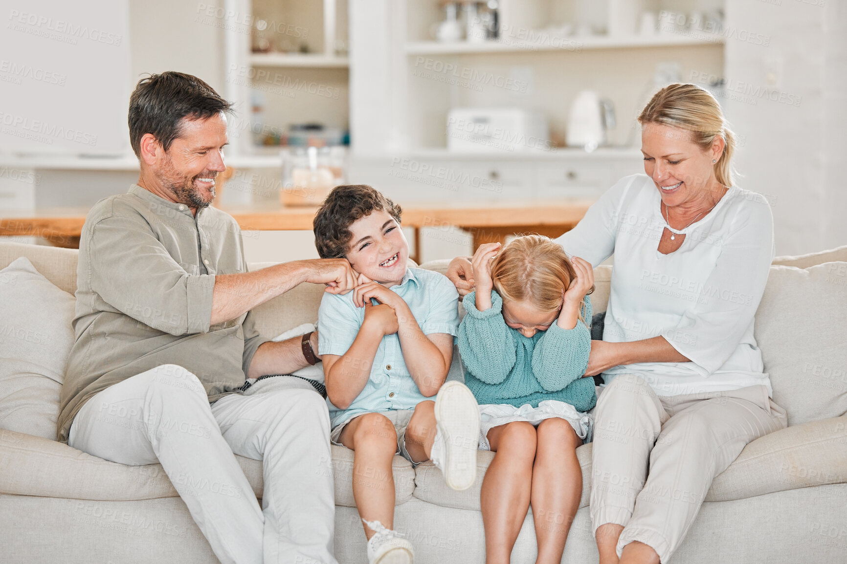 Buy stock photo Parents, kids and laughing for playing on sofa with tickle, affection and happy relationship in home. Family, people and children on couch with bonding, connection and enjoyment for love and care