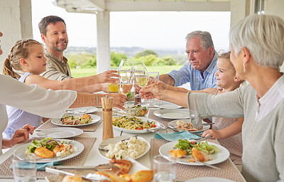 Buy stock photo Shot of a family toasting during a sunday lunch