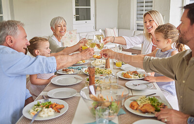 Buy stock photo Shot of a family toasting during a sunday lunch
