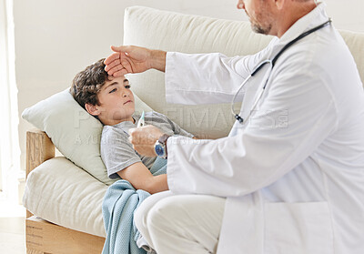 Buy stock photo Shot of a male doctor taking a little boys temperature at home