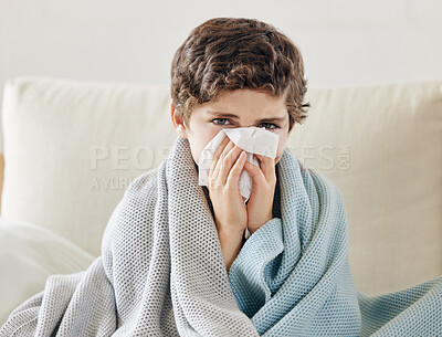 Buy stock photo Shot of a little boy blowing his nose and looking sick while sitting on the sofa at home