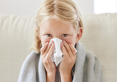 Buy stock photo Shot of a little girl blowing her nose and looking sick while sitting on the sofa at home