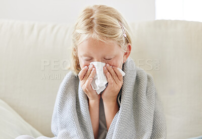 Buy stock photo Shot of a little girl blowing her nose and looking sick while sitting on the sofa at home