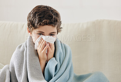 Buy stock photo Shot of a little boy blowing his nose and looking sick while sitting on the sofa at home