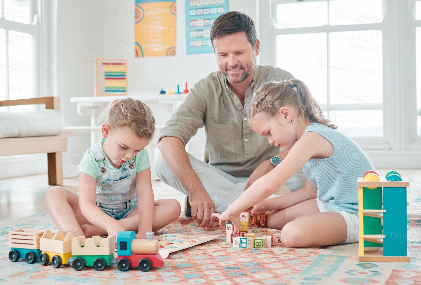 Buy stock photo Shot of a father sitting with his two daughters while they play with their toys