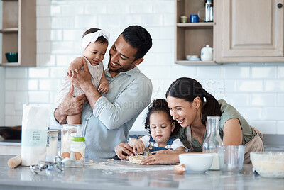 Buy stock photo Shot of a woman baking in the kitchen with her husband and two daughters
