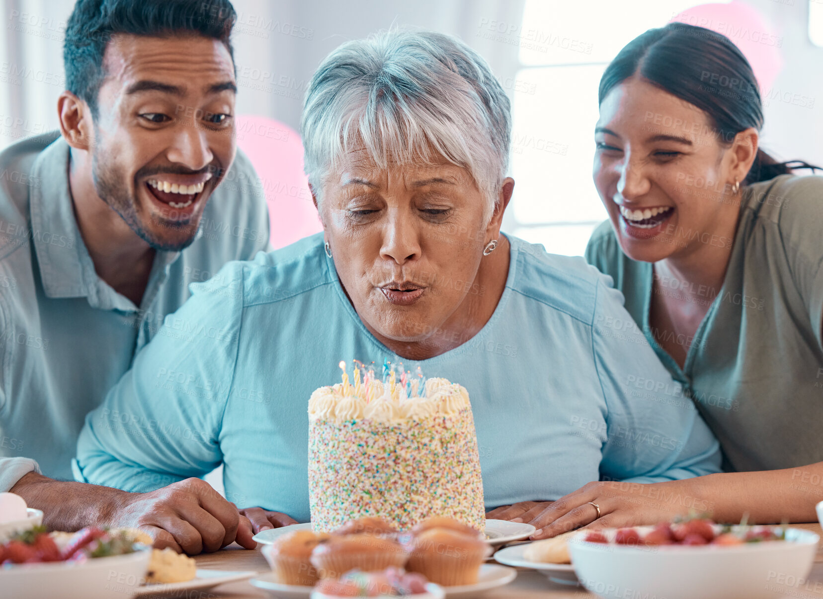 Buy stock photo Shot of two young adults celebrating a birthday with a mature woman at home