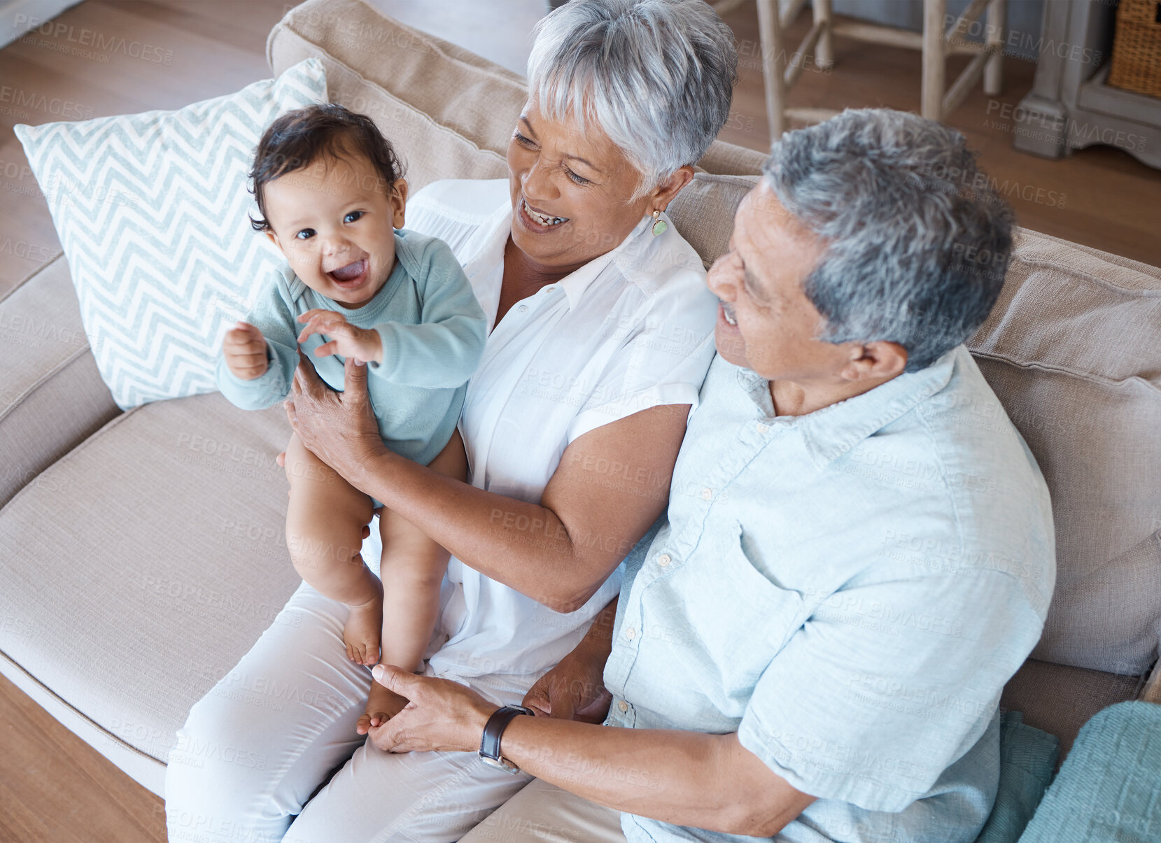 Buy stock photo Relax, above and grandparents with baby on sofa for bonding, laughing and support. Love, happiness and generations with senior man and woman holding child in living room of family home together