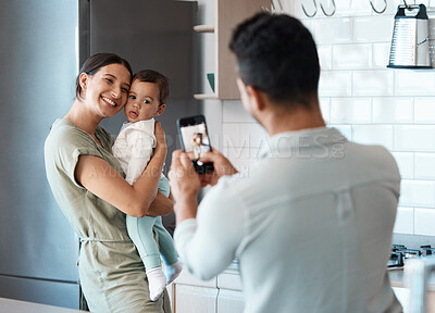 Buy stock photo Shot of a young mother taking a picture with her baby at home