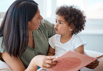 Buy stock photo Shot of a young mother and daughter reading a book together at home