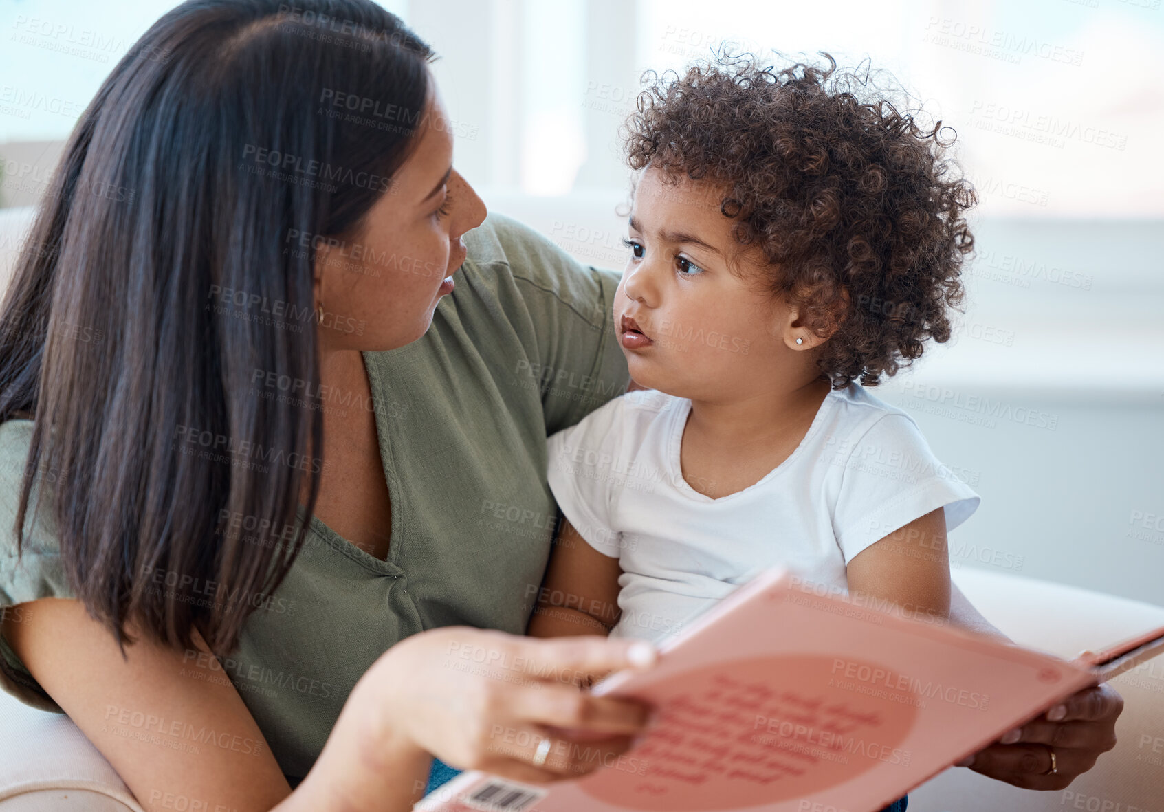 Buy stock photo Shot of a young mother and daughter reading a book together at home