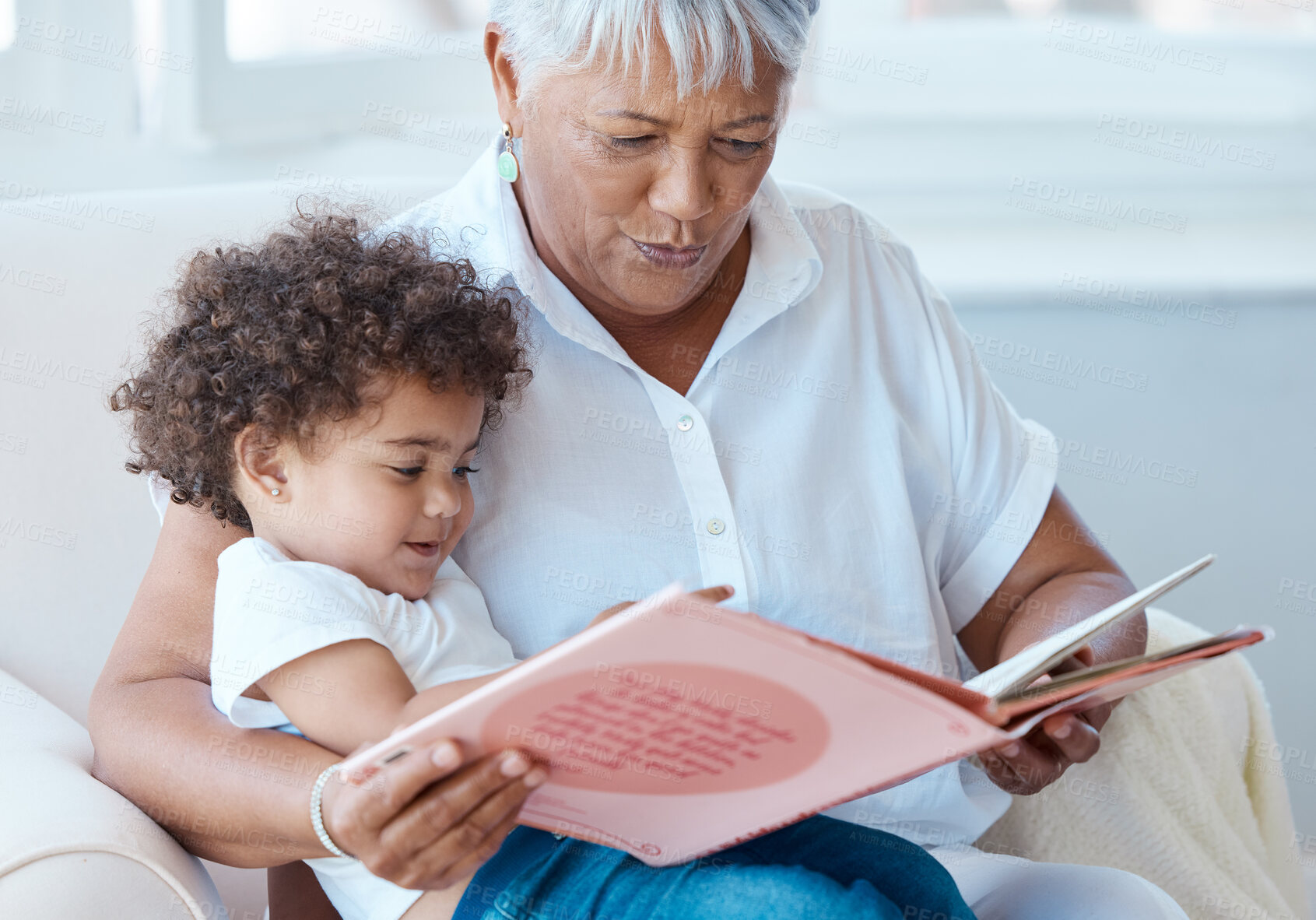Buy stock photo Shot of a mature grandmother reading her granddaughter a story at home