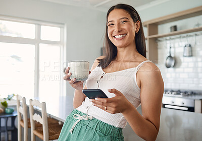 Buy stock photo Shot of a woman holding her cellphone while drinking coffee at home