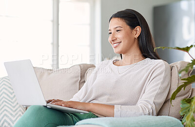 Buy stock photo Shot of a beautiful young woman using her laptop while sitting on the couch at home