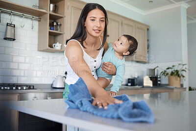 Buy stock photo Shot of a woman cleaning her house with her baby on her arm