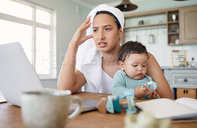 Buy stock photo Shot of a woman looking stressed while looking at her laptop and holding her baby on her lap