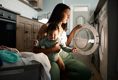 Buy stock photo Shot of a mom doing laundry at night with her baby on her arm