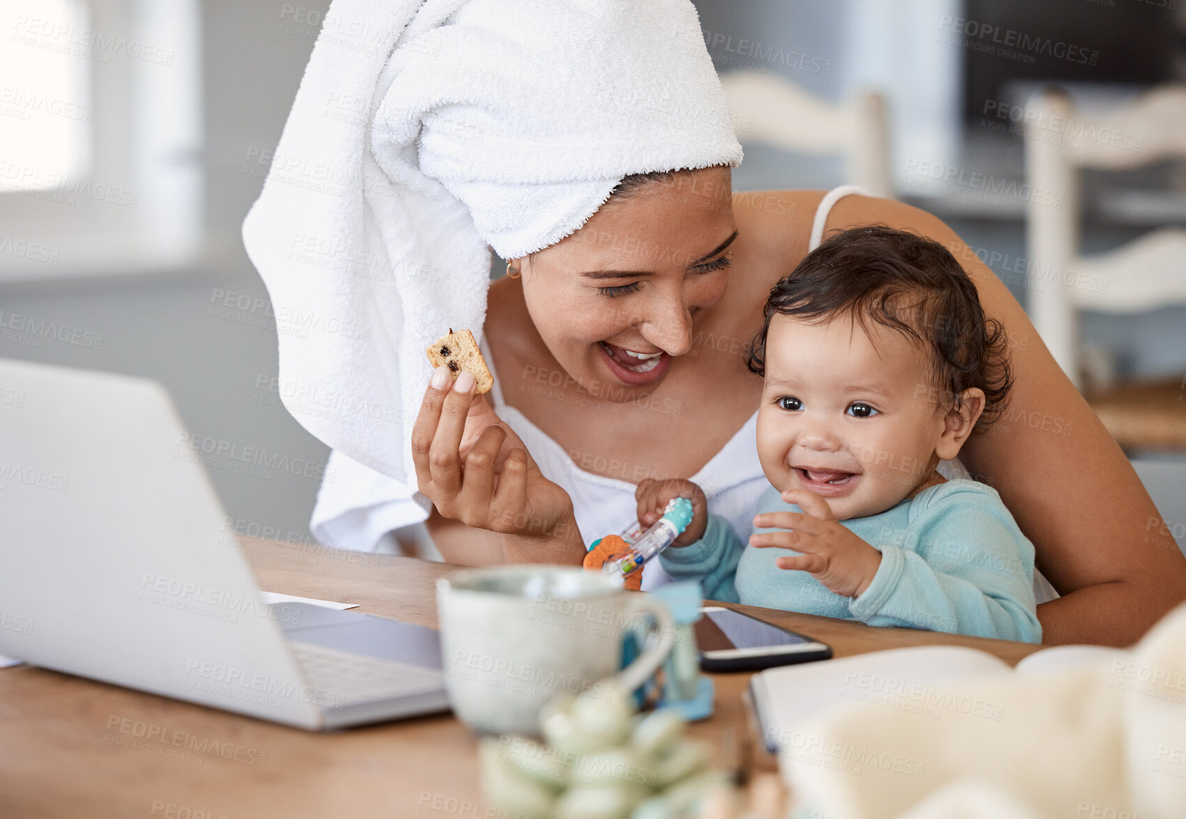 Buy stock photo Shot of a woman eating rusks while working on her laptop and holding her baby on her lap