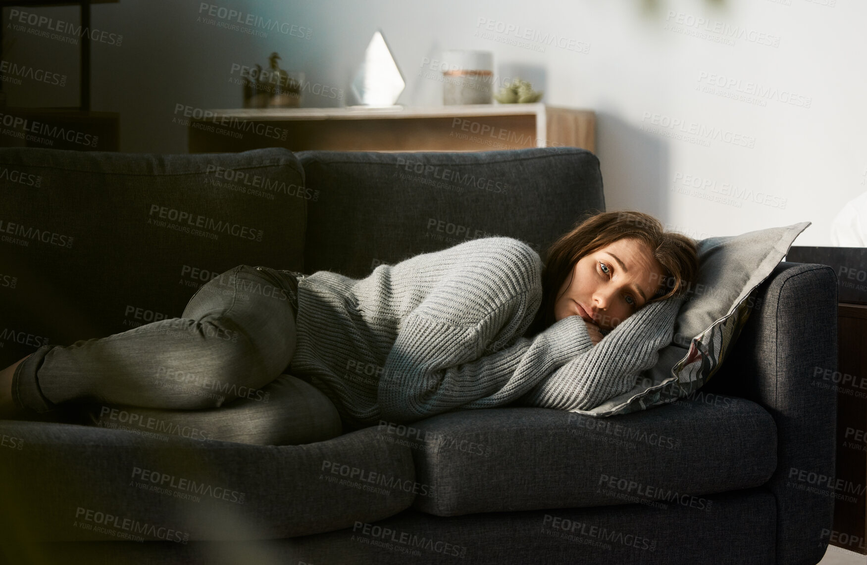 Buy stock photo Shot of a young woman lying on her couch feeling depressed