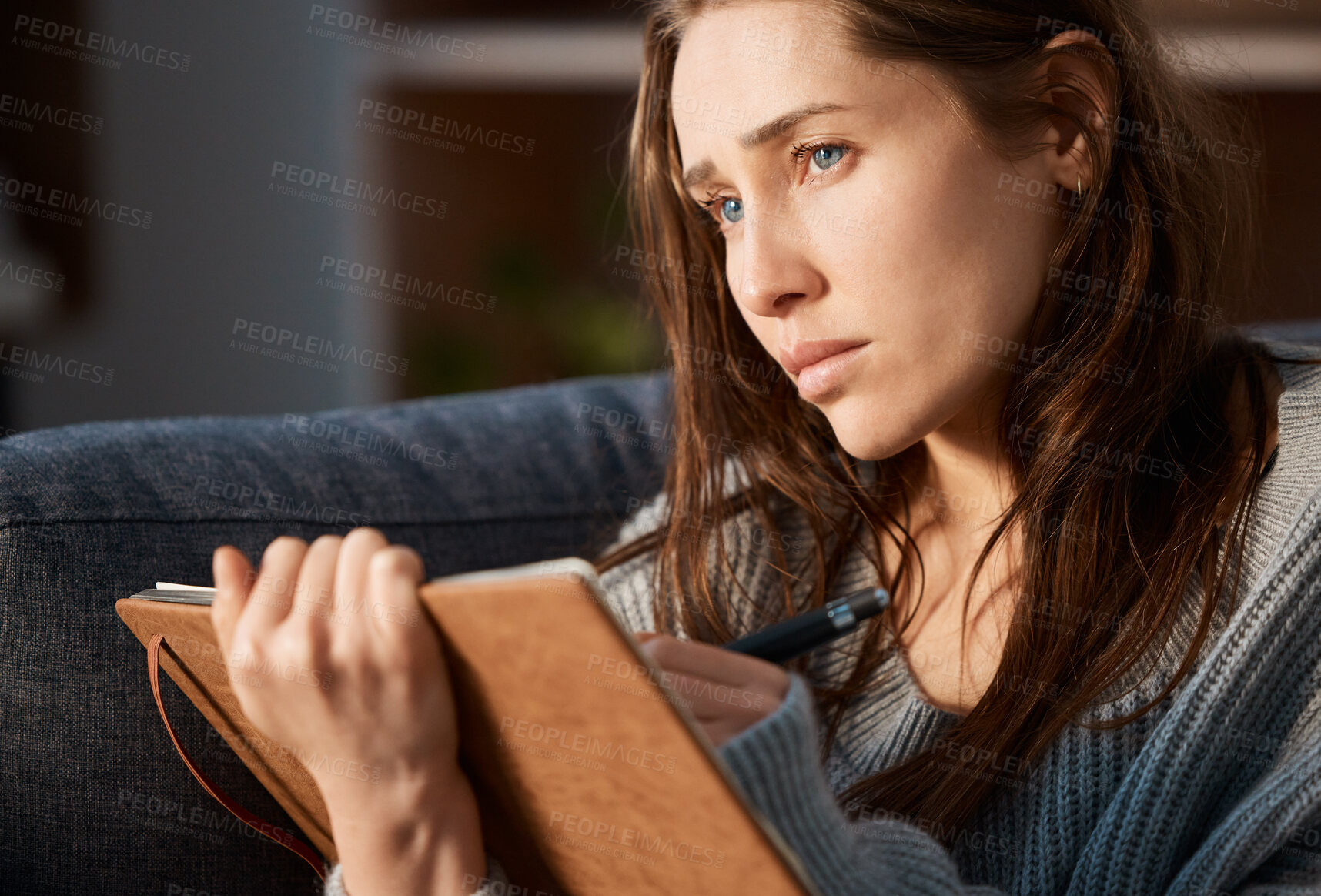 Buy stock photo Shot of an anxious young woman writing in her journal