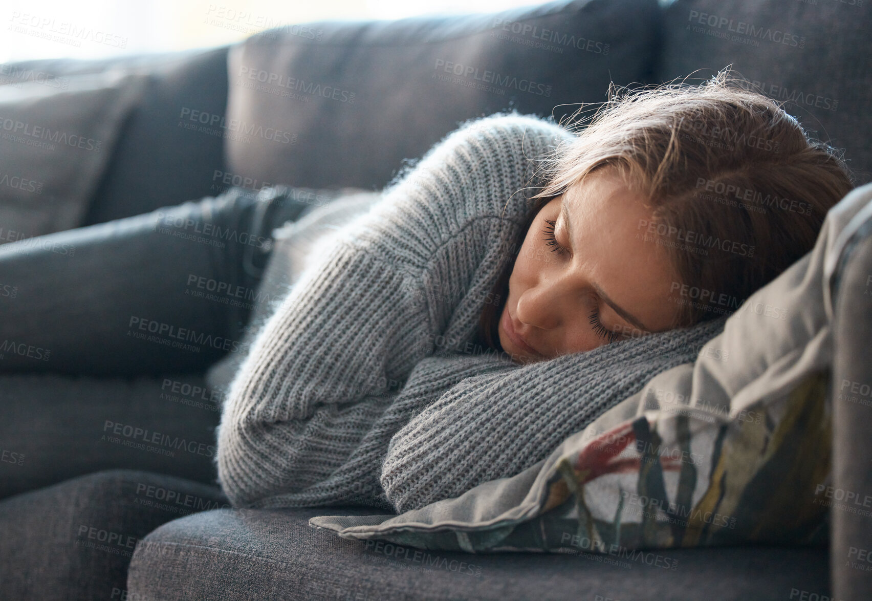 Buy stock photo Shot of a young woman lying on her couch feeling depressed