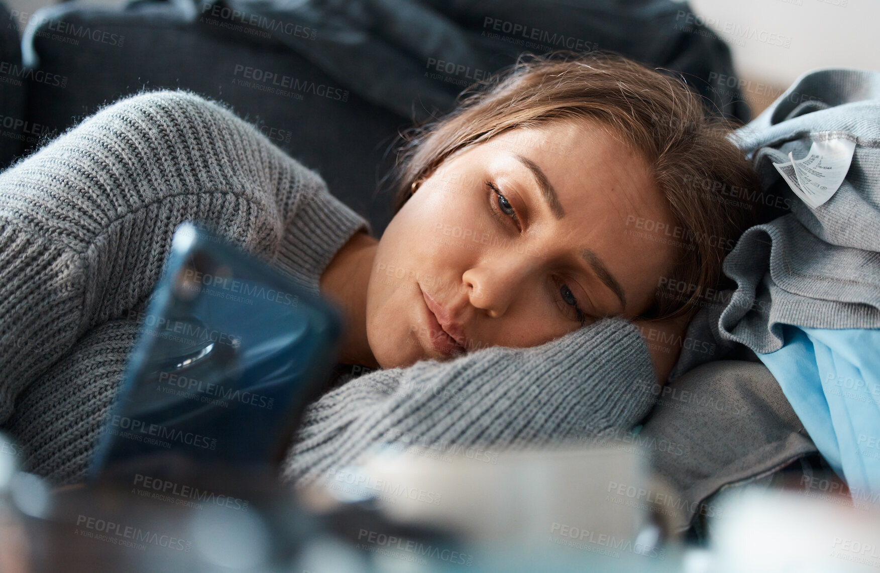 Buy stock photo Shot of a young woman looking depressed while using her smartphone