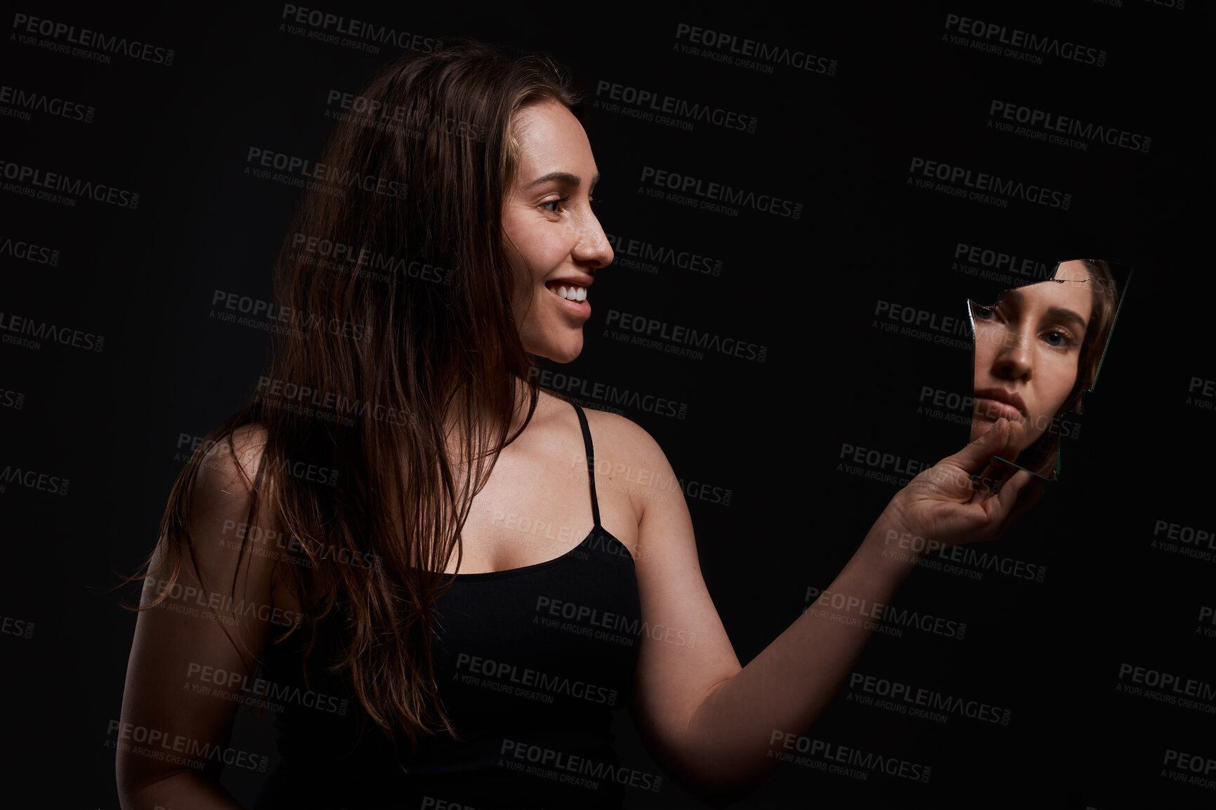 Buy stock photo Shot of a creepy woman grinning at her reflection in a broken mirror