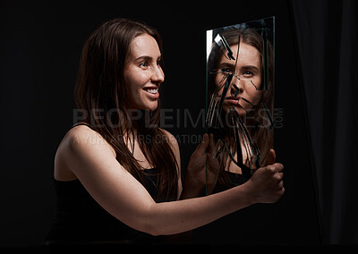 Buy stock photo Shot of a creepy woman grinning at her reflection in a broken mirror