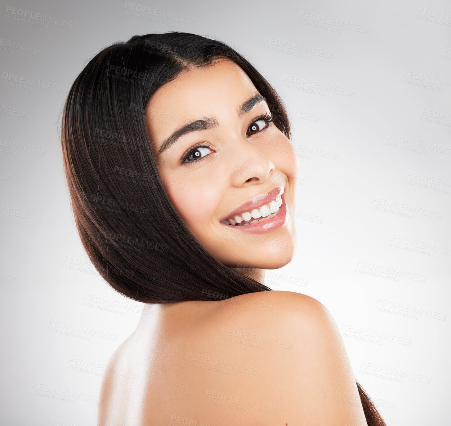 Buy stock photo Studio portrait of a beautiful young woman showing off her long silky hair against a grey background