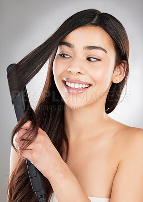Buy stock photo Studio shot of a beautiful young woman styling her hair against a grey background